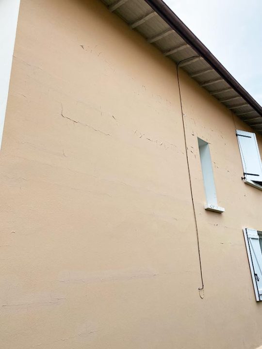 Vue sur la façade Nord de la maison qui présente de la peinture écaillée et des micro-fissures.
